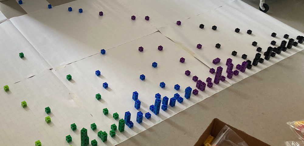 Photo of Hana's multilink cube version of Number City, laid out on a piece of paper on the floor