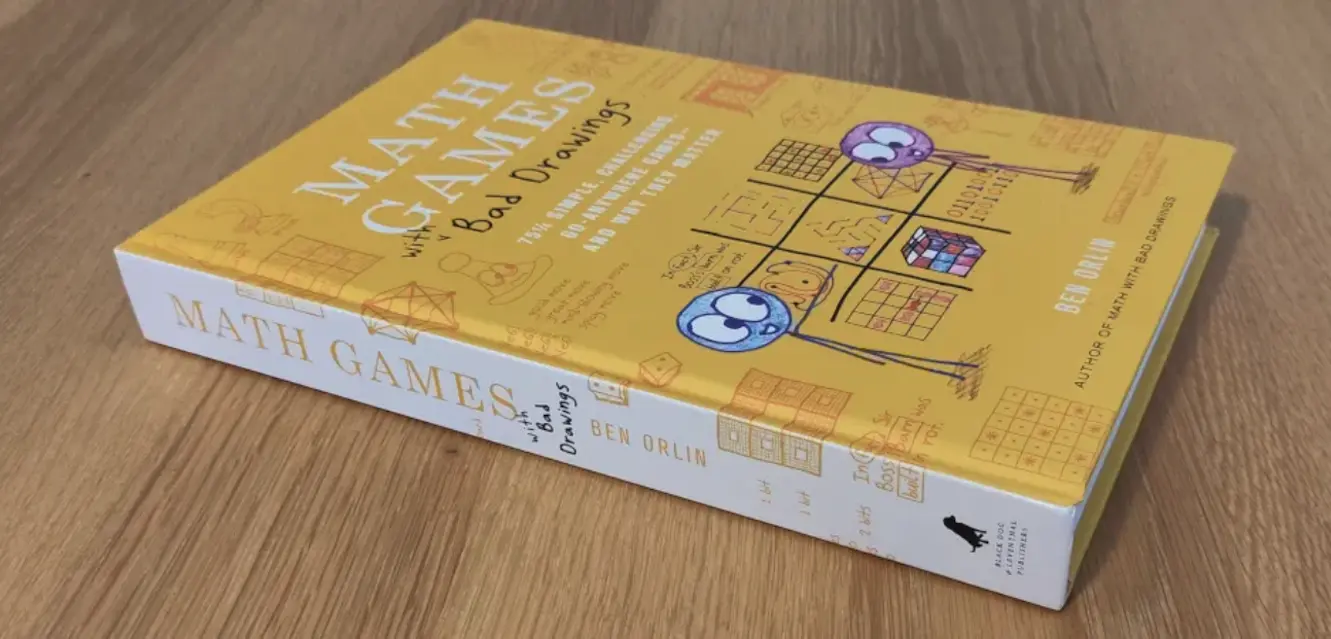 Photo of Ben's book Math Games with Bad Drawings, which is yellow and has stick figure drawings on the front. It is quite big
